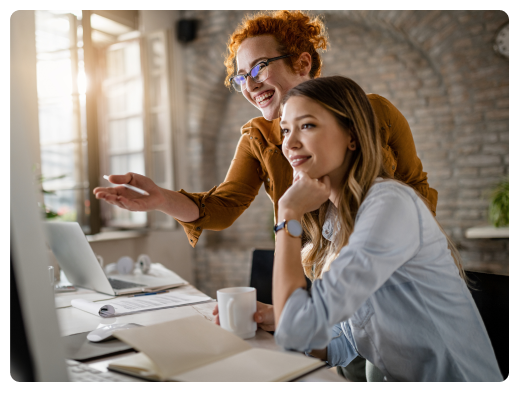 happy-female-entrepreneurs-reading-email-computer-while-working-together-office-focus-is-redhead-woman 1